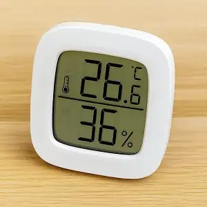 Termohigrómetro digital barato y compacto encima de una mesa de madera de color claro