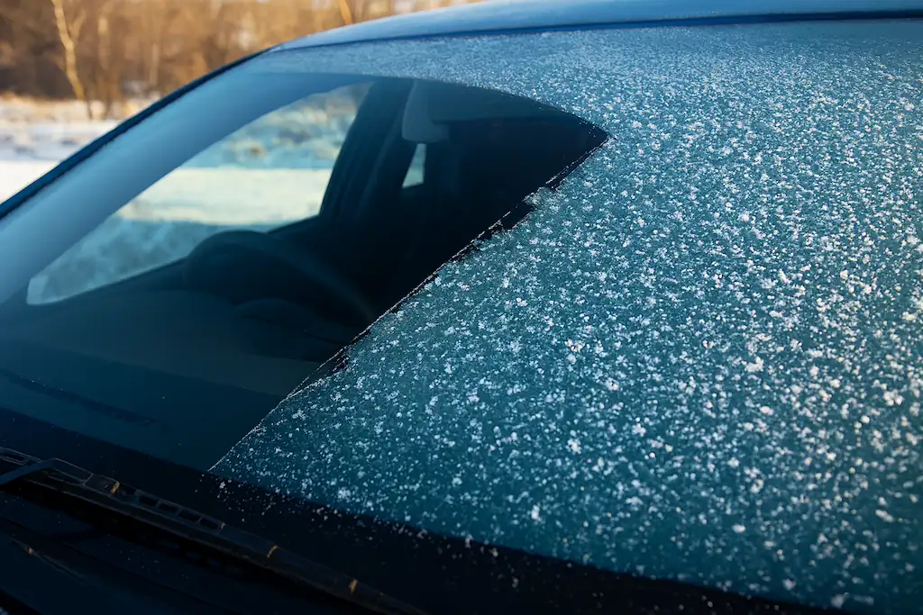 El parabrisas de un coche en primer plano con escarcha, mostrando cómo el vapor de agua se ha congelado directamente. Para ilustrar el concepto de punto de rocío bajo cero