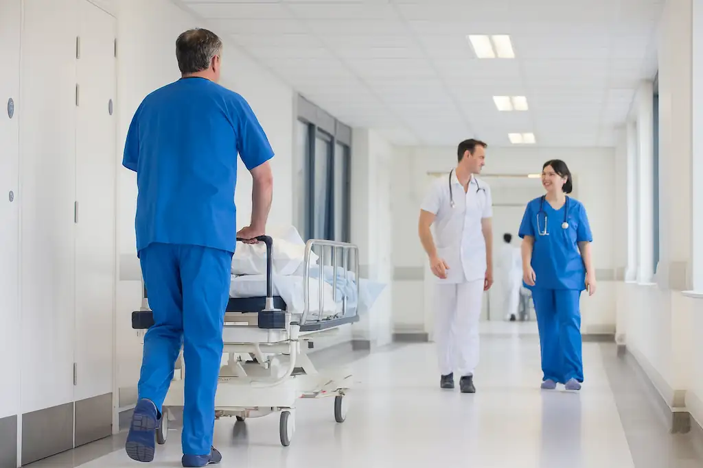 Personal médico en un pasillo de hospital con control de humedad absoluta, con un enfermero empujando una camilla y dos profesionales conversando mientras caminan